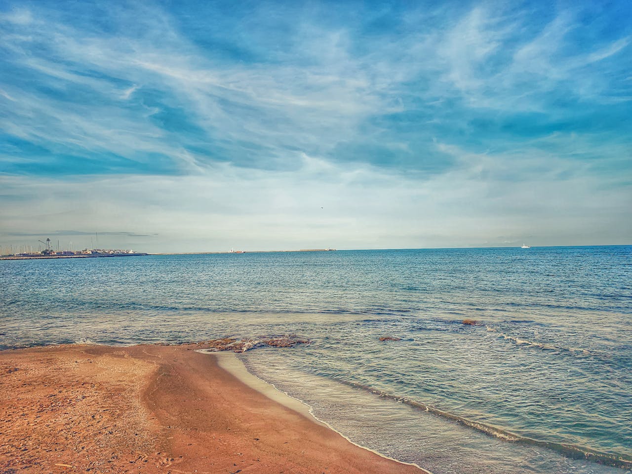 Scenic view of a serene Spanish beach with azure waters under a clear blue sky, perfect for travel and relaxation.